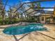 Inviting outdoor pool with a screened enclosure, surrounded by lush greenery and a landscaped yard at 2806 Forest Club Dr, Plant City, FL 33566