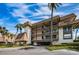 Attractive condominium complex featuring multiple stories, balconies, and lush landscaping with mature palm trees against a bright blue sky at 3021 Countryside Blvd # 26A, Clearwater, FL 33761