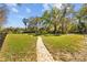 A stone pathway leads through a large backyard with mature trees at 3114 Bluff Blvd, Holiday, FL 34691