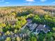 A high angle view of large homes nestled in a verdant, mature forest with long, winding driveways under a partly cloudy sky at 3198 Thatcher Ln, Tarpon Springs, FL 34688