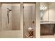 Bathroom with a frameless glass shower, tile surround, and granite vanity with a wood base at 3198 Thatcher Ln, Tarpon Springs, FL 34688