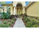 Charming front entrance with a brick path, green plants, and glass-accented double doors at 3198 Thatcher Ln, Tarpon Springs, FL 34688