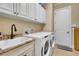 Laundry room showcasing white washer and dryer, granite sink and storage at 3198 Thatcher Ln, Tarpon Springs, FL 34688