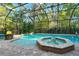 A refreshing screened-in pool and spa are surrounded by brick pavers and lush landscaping at 3198 Thatcher Ln, Tarpon Springs, FL 34688