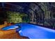Beautiful in-ground pool and hot tub with screened enclosure, surrounded by patio area and lush landscaping at 3198 Thatcher Ln, Tarpon Springs, FL 34688