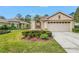 Well-maintained single-story home with green lawn, manicured shrubbery, and an ADT security sign at 3215 Banyan Hill Ln, Land O Lakes, FL 34639