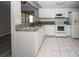 This is a kitchen with white appliances, granite countertops, and white tile floors at 3603 Darlington Rd, Holiday, FL 34691