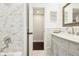 Elegant bathroom featuring marble tiling, a vanity with lots of storage and a decorative mirror at 4027 Benson N Ave, St Petersburg, FL 33713