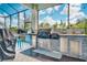 Outdoor kitchen with stainless steel appliances and a stone countertop for backyard entertaining at 4926 Pamplona Ct, Wimauma, FL 33598