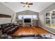 Open-concept living room features wood floors, large windows, ceiling fan, and comfortable leather couches at 5123 Whispering Leaf Trl, Valrico, FL 33596