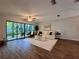 Bright living room features wood floors, fan, neutral walls, and large window overlooking patio with garden views at 610 S Woodlands Dr, Oldsmar, FL 34677