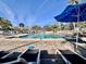 Relax by the community pool in lounge chairs under a blue umbrella on a sunny day at 610 S Woodlands Dr, Oldsmar, FL 34677