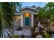 Inviting front entrance with a bright turquoise door, stone pathway, and lush tropical landscaping at 8038 27Th N Ave, St Petersburg, FL 33710