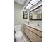 Bathroom with modern vanity, white toilet, skylight for natural lighting, and neutral paint at 908 Rosewood Ln, Palm Harbor, FL 34684