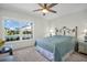 Bedroom with a comfortable queen bed, soft carpet, a ceiling fan, and large window for natural light at 908 Rosewood Ln, Palm Harbor, FL 34684
