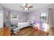 Comfortable bedroom with lavender colored walls, light wood floors, ceiling fan, and well-lit windows at 910 Edgedale Cir, Brandon, FL 33510
