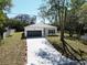 An elevated view showcasing the home's clean white exterior, long driveway, and surrounding greenery at 9445 Eldridge Rd, Spring Hill, FL 34608