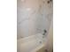 Full bathroom highlighting marble-look tiled walls and bathtub with shower combination at 9445 Eldridge Rd, Spring Hill, FL 34608