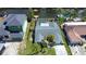 Aerial view of a home with a screened-in pool, a dock, and water access, surrounded by lush landscaping at 9826 Island Harbor Dr, Port Richey, FL 34668