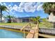 Waterfront backyard with a screened-in pool, a dock, and a lush lawn leading to the water at 9826 Island Harbor Dr, Port Richey, FL 34668