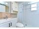 Bright bathroom with a white vanity and shower with neutral tiling at 9826 Island Harbor Dr, Port Richey, FL 34668