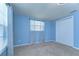 Bedroom features neutral carpet, blue walls, and double closet at 9826 Island Harbor Dr, Port Richey, FL 34668
