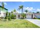 Well-maintained single-story home with an attached garage, lush landscaping, and a manicured lawn under a bright sky at 9826 Island Harbor Dr, Port Richey, FL 34668