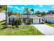 Charming single-story home with a well-maintained lawn, tropical landscaping, and an attached garage on a sunny day at 9826 Island Harbor Dr, Port Richey, FL 34668