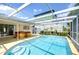 The caged pool is surrounded by tan stone and has a ladder entry at 9826 Island Harbor Dr, Port Richey, FL 34668
