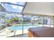 Screened-in pool area features a swimming pool, canal view, hot tub, and stone flooring for outdoor relaxation at 9826 Island Harbor Dr, Port Richey, FL 34668
