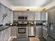 This kitchen is equipped with stainless steel appliances, granite countertops, and gray cabinetry at 7910 Sun Island S Dr # 301, South Pasadena, FL 33707