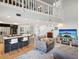 Open-concept living room with island bar and fireplace, featuring modern decor, a large TV, and a split staircase at 115 16Th St, Belleair Beach, FL 33786