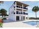 A stylish white home features a pool, multi-level balconies, and well-manicured tropical landscaping at 2004 Gulf Blvd, Indian Rocks Beach, FL 33785