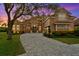 An impressive home at dusk features a paved driveway, a terracotta roof, and a manicured lawn at 20104 Fair Hill Way, Tampa, FL 33647