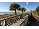 Scenic boardwalk leading to a beautiful beach with clear blue water and palm trees at 26 Clintwood Ave, Englewood, FL 34223