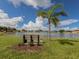 A peaceful park bench sits beneath a palm tree overlooking a tranquil lake with fountain feature at 26 Clintwood Ave, Englewood, FL 34223