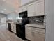 Stylish kitchen featuring granite countertops, backsplash, black appliances, and white cabinetry, a chef's dream at 26 Clintwood Ave, Englewood, FL 34223