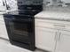 The kitchen features a black stove with modern white cabinets and drawers, plus stylish gray countertops and tile backsplash at 26 Clintwood Ave, Englewood, FL 34223