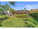 Large backyard with green grass, a privacy fence, landscaping, and a screen enclosed pool with an outdoor sitting area at 3442 Beech Trl, Clearwater, FL 33761