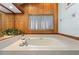 A soaking tub features tile surround, wood paneling and a large window with natural light and plants at 3442 Beech Trl, Clearwater, FL 33761