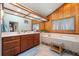 Bathroom featuring double sinks, soaking tub and adjacent wood paneled walls under a vaulted ceiling at 3442 Beech Trl, Clearwater, FL 33761