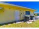 The back of the home has a white door, AC unit, and trash cans near a green lawn at 5427 Springwood Blvd # 5427, Pinellas Park, FL 33782
