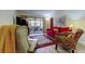 Inviting living room with red sofa and colorful accent chair, leading to a screened patio at 9769 86Th Ave # 9769, Seminole, FL 33777
