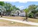 Charming two-story home with a well-manicured lawn and lush palm trees on a sunny day at 1037 Jamaica Way, Tarpon Springs, FL 34689