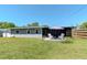 Back exterior showcasing the home's screened-in porch and a patio with a sun umbrella and white outdoor chairs at 13596 Croft N Dr, Largo, FL 33774