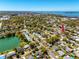 Expansive aerial view showcasing the neighborhood's mature trees, a pond, and proximity to the bay at 1521 San Helen Dr, Dunedin, FL 34698