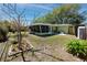 Large, grassy back yard featuring an enclosed porch, garden bed, and partial privacy fencing at 1521 San Helen Dr, Dunedin, FL 34698