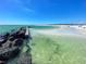 Calm clear water washing on a pristine beach with a rock wall and plenty of room for visitors at 1521 San Helen Dr, Dunedin, FL 34698