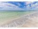 Picturesque beach featuring clear, shallow water, soft sand, and a seagull in flight along the shoreline at 1521 San Helen Dr, Dunedin, FL 34698