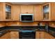 Gourmet kitchen featuring granite countertops, natural wood cabinets, and modern appliances at 1521 San Helen Dr, Dunedin, FL 34698